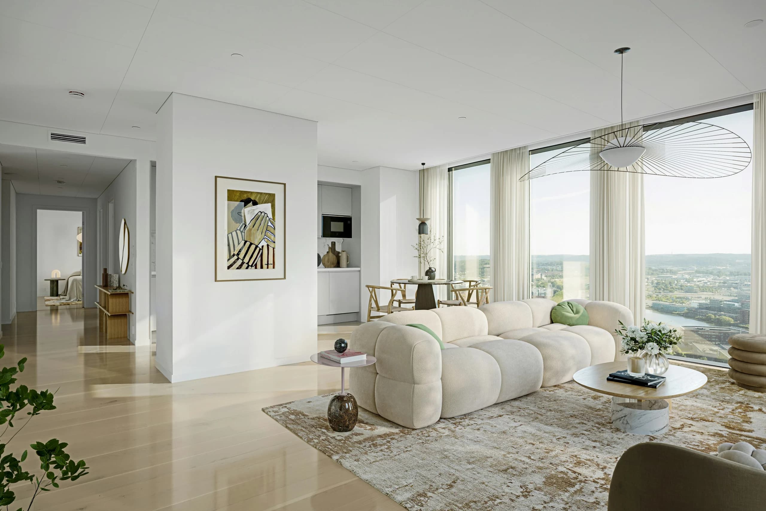 Cream rounded sofa on a patterned rug in an open living and dining room with full-height windows and a wide pendant